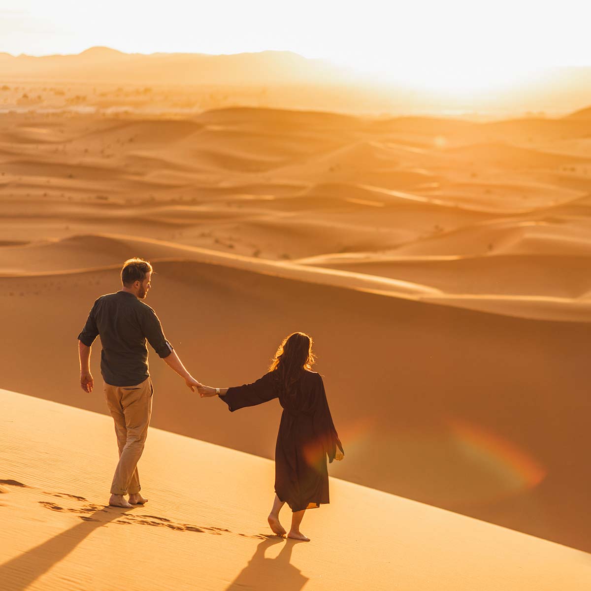 couple-walking-in-sahara-desert-at-sunset-view-fr-CAUWRM2.jpg